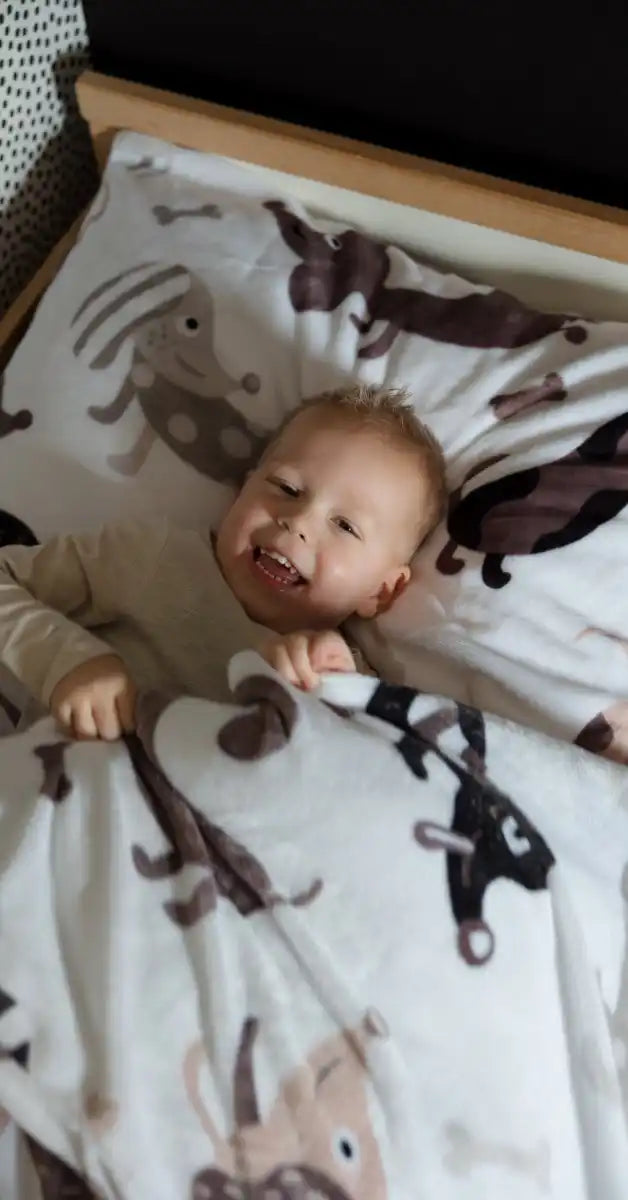 Baby ligt op een deken met aapjespatronen.