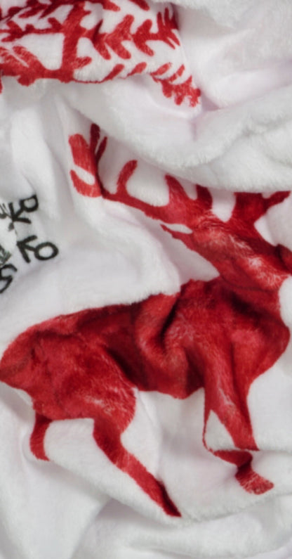 Close-up van een wit kerstplaid van zachte velvet stof, versierd met gedetailleerde afbeeldingen van rendieren, kerstbomen en sneeuwvlokken. Het plaid straalt winterse gezelligheid en luxe uit. foto: stof kerst plaid.