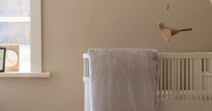 Close-up van een taupe velvet dekbedovertrek dat hangend over een ledikantje in een babykamer. Het zachte materiaal glanst lichtjes in het warme licht van de kamer, terwijl de schaduw van het dekbedovertrek de structuur van de stof accentueert.
foto: ledikant dekbedovertrek taupe 