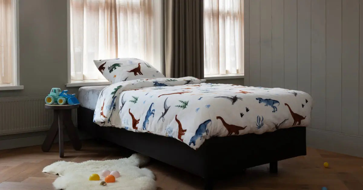 Velvet dekbedovertrek voor peuters met een schattig dino-ontwerp op een witte achtergrond. Het dekbedovertrek toont kleurrijke dinosaurussen in verschillende vormen en maten, ideaal voor een kinderkamer. foto: peuter dekbedovertrek dino op een bed.