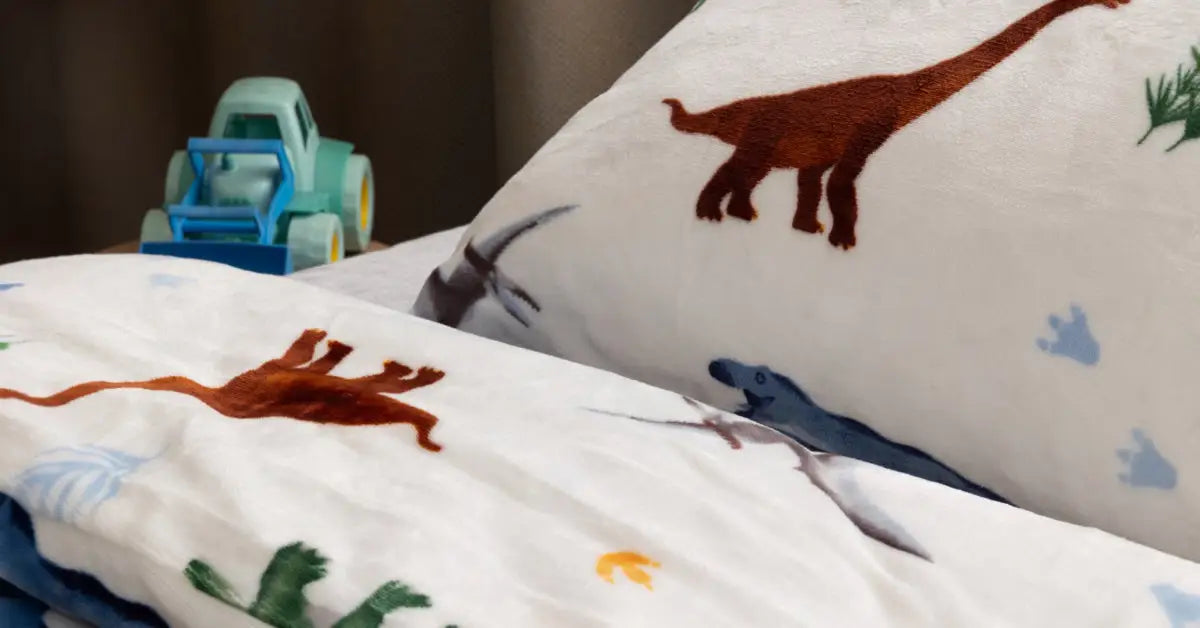 Close-up van een zacht velvet peuter dekbedovertrek met dino-print, mooi opgemaakt op een bed in een gezellige kamer. Naast het bed staat een schattige auto, wat een speelse sfeer toevoegt aan de ruimte.
foto: peuter dekbedovertrek dino met auto