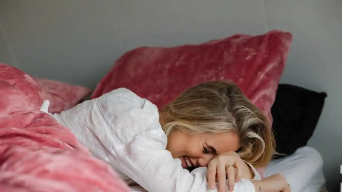 Lachende vrouw in bed.